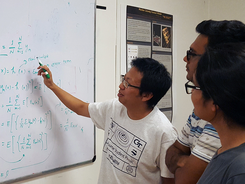 Three people gather at a whiteboard.