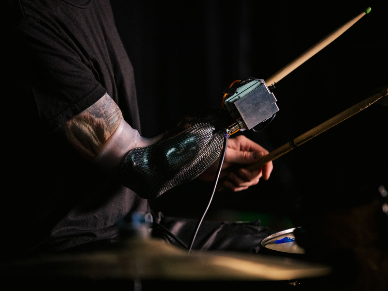 man with a customized prosthetic arm playing drums